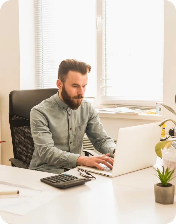 Man working on laptop in bright office, used for “How Our Specialists Work” section.